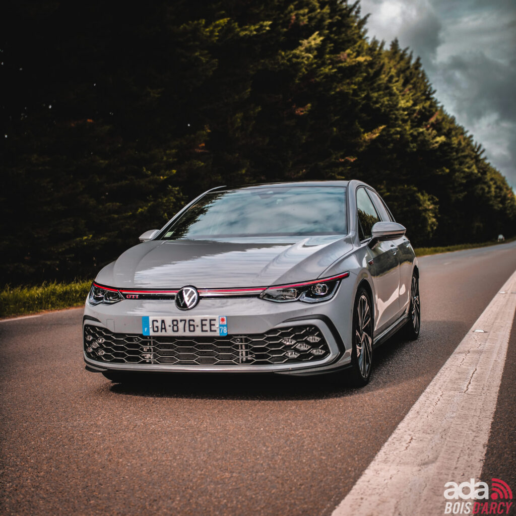 Golf 8 GTI grise sur une route bordée d'arbres