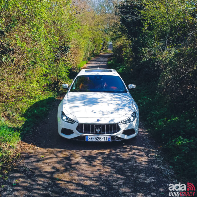 Maserati Ghibli SQ4 blanche vue de face sur un chemin bordé de verdure, pour une escapade depuis l'Essonne