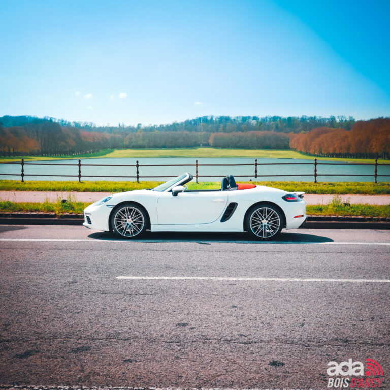 Porsche Boxster 718 blanc capote ouverte au bord d'un grand parc, cabriolet à louer dans les Yvelines